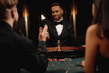 A professional dealer in a tuxedo greeting players at the roulette table, symbolizing the authentic live casino feel at WA777.