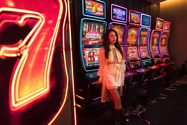 A stylish woman beside vibrant slot machines displaying glowing sevens, showcasing the variety of top slots at WA777.